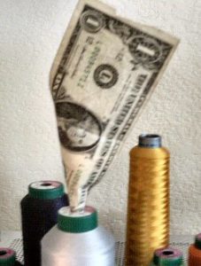 money sticking up out of a spool of thread